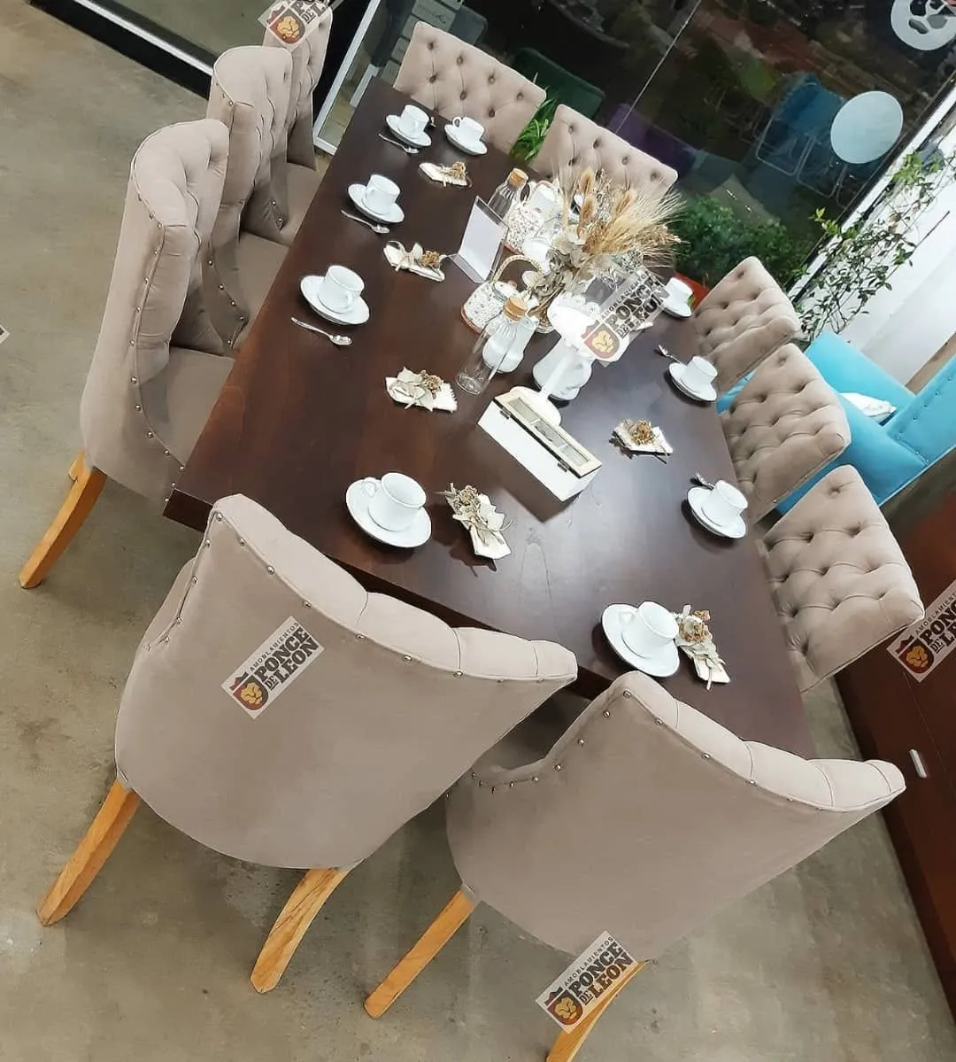 Comedor con mesa de madera y sillas capitoné en el showroom de Amoblamientos Ponce de León
